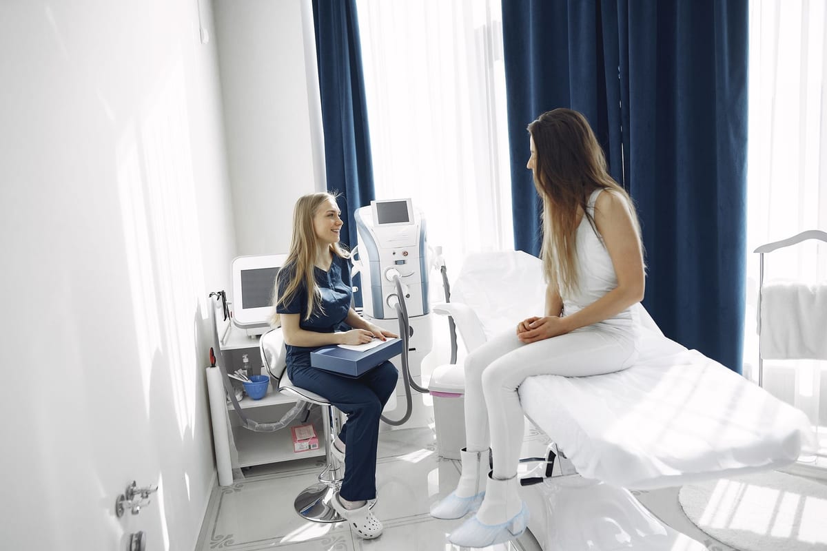 A woman seated on an exam bed talking with a clinician