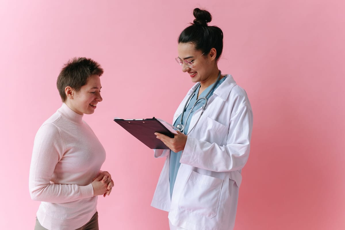 A doctor talking with a smiling woman, clipboard in hand
